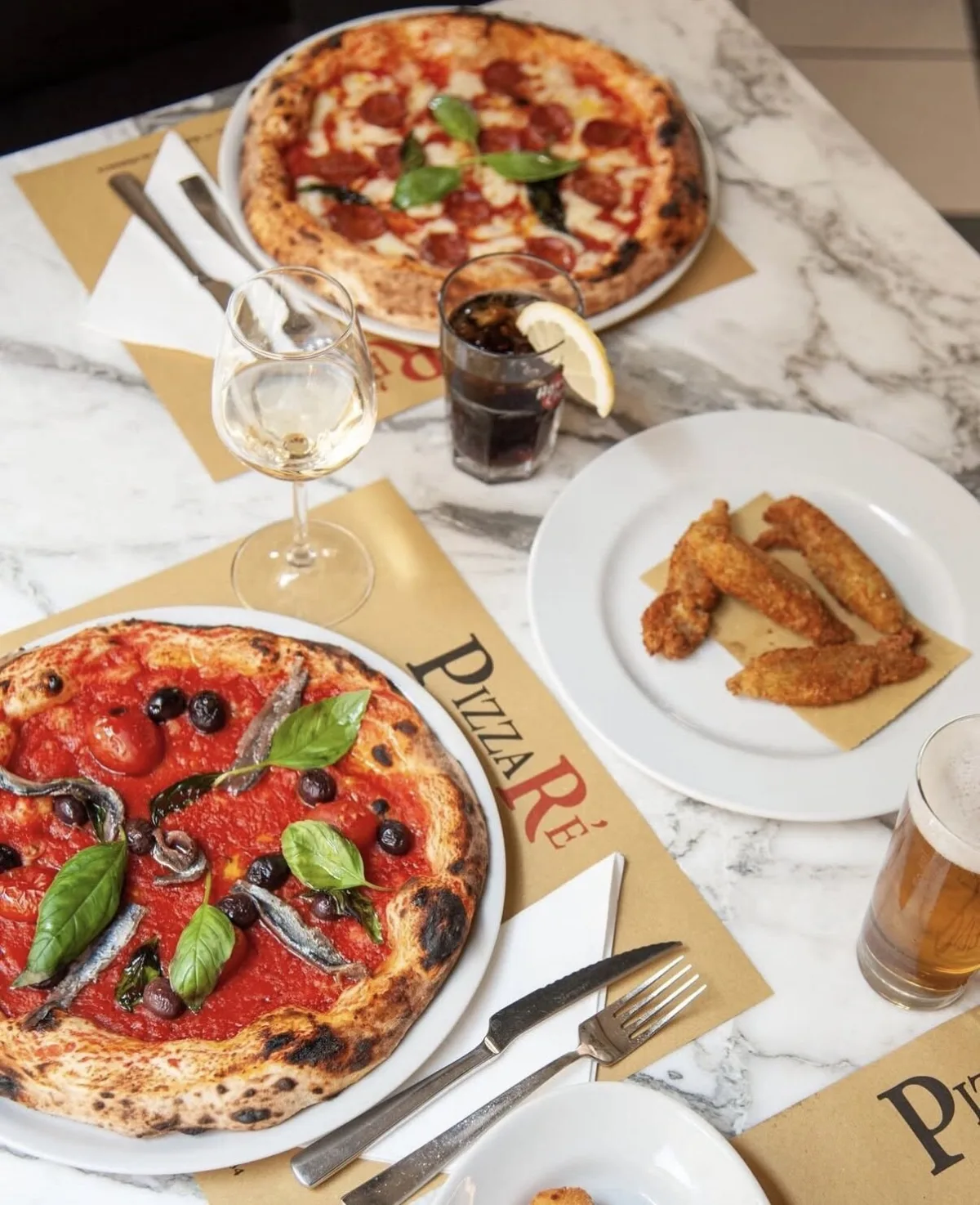 Tavolo di marmo con Puttanesca, Diavolina e fiori di zucca fritti, su tovagliette PizzaRé